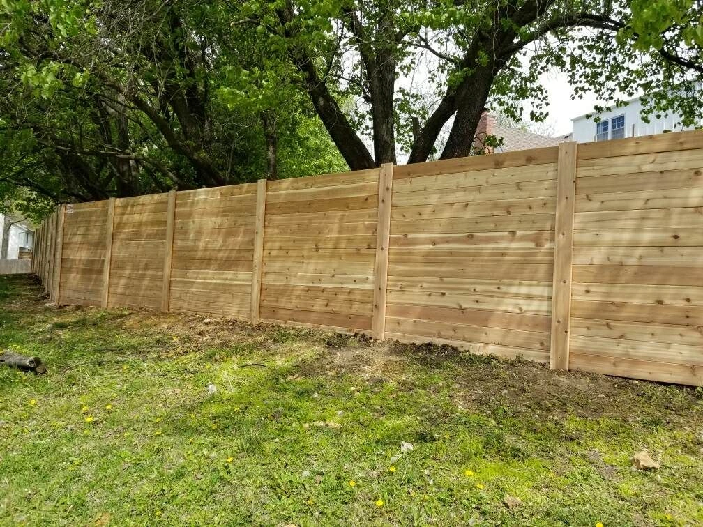 Horizontal cedar privacy fence installed beneath mature trees
